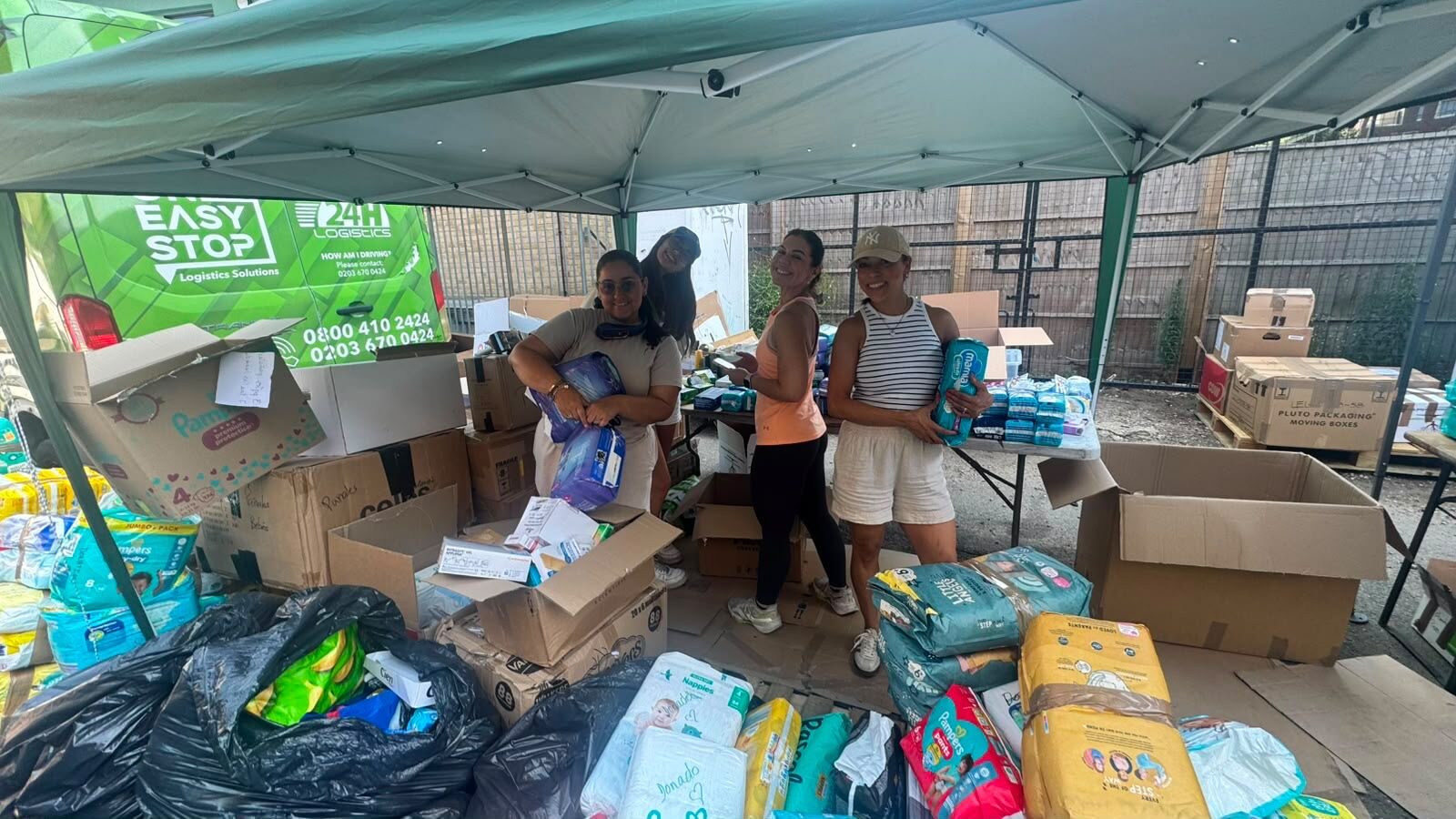Volunteers sorting aid at a collection point with a logistics partner's van